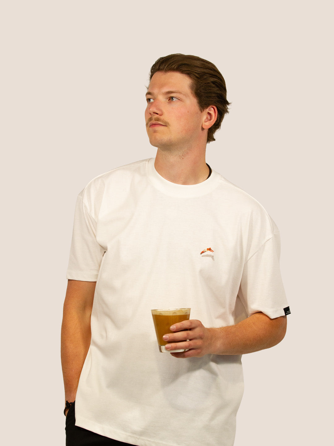 Mann im Off-White Heavy Tee „How To Stay Awake Forever“ von Bengel & Göre mit Eiskaffee, Brust-Stick vorn.