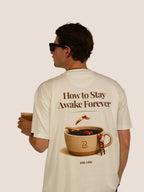 Rückseite des Off-White Heavy Tee „How To Stay Awake Forever“ mit Kaffeetassen-Print, Mann mit Eiskaffee.