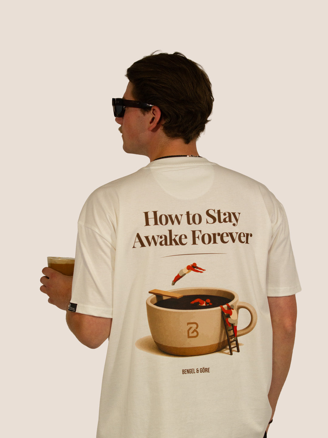 Rückseite des Off-White Heavy Tee „How To Stay Awake Forever“ mit Kaffeetassen-Print, Mann mit Eiskaffee.