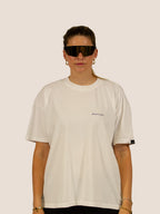 Frau im Off-White Heavy Tee von Bengel & Göre mit Brust-Schriftzug und Rennrad-Sonnenbrille, Vorderseite.