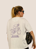 Rückseite des Off-White Heavy Tee „Fast Mornings and Bad Decisions“ mit lila Rennrad-Print, Frau mit Helm.