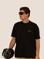Mann im schwarzen Bengel & Göre Heavy Tee mit Brust-Schriftzug, Rennrad-Brille und POC-Helm, Vorderseite.