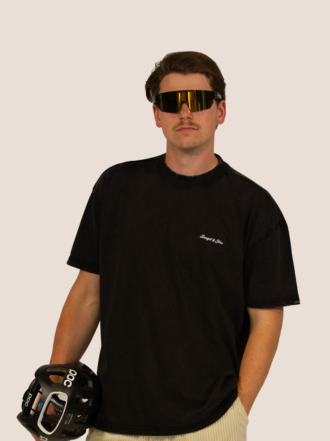 Mann im schwarzen Heavy Tee von Bengel & Göre mit Sport-Sonnenbrille und Radhelm, Brust-Schriftzug vorn.