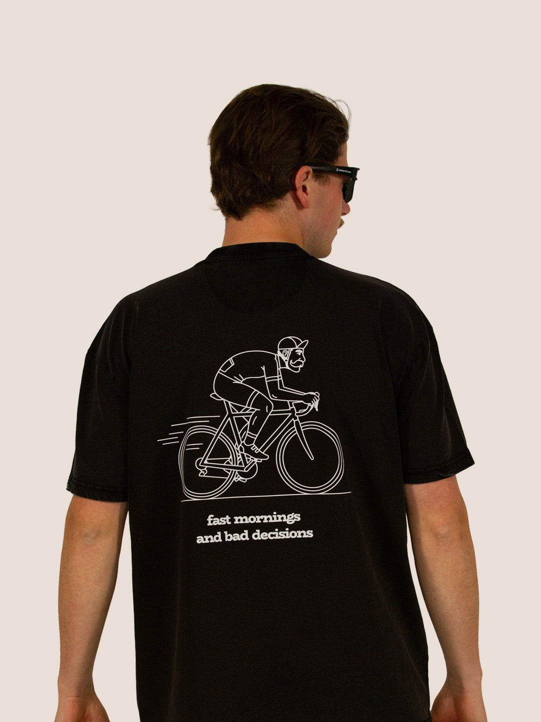 Rückseite des schwarzen Heavy Tee „Fast Mornings and Bad Decisions“ mit weißer Rennrad-Line-Art, Mann.