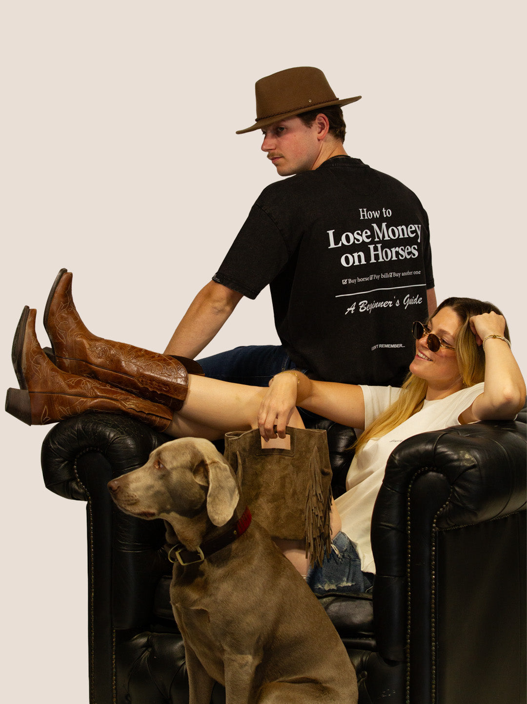 Paar in Bengel & Göre „Horses“ Heavy Tees auf Ledersessel mit Cowboystiefeln und Weimaraner-Hund.