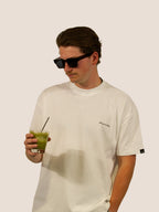 Mann im Off-White Heavy Tee von Bengel & Göre mit Matcha-Drink und Sonnenbrille, Kyoto Morning Matcha Club.