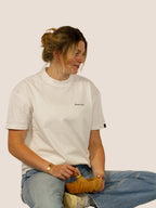 Frau im Off-White Bengel & Göre Heavy Tee mit Matcha-Schale und Bambusbesen, Vorderseite.