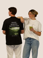 Mann im schwarzen „Kyoto Morning Matcha Club“ Heavy Tee, Frau in Off-White mit Matcha, Bengel & Göre.