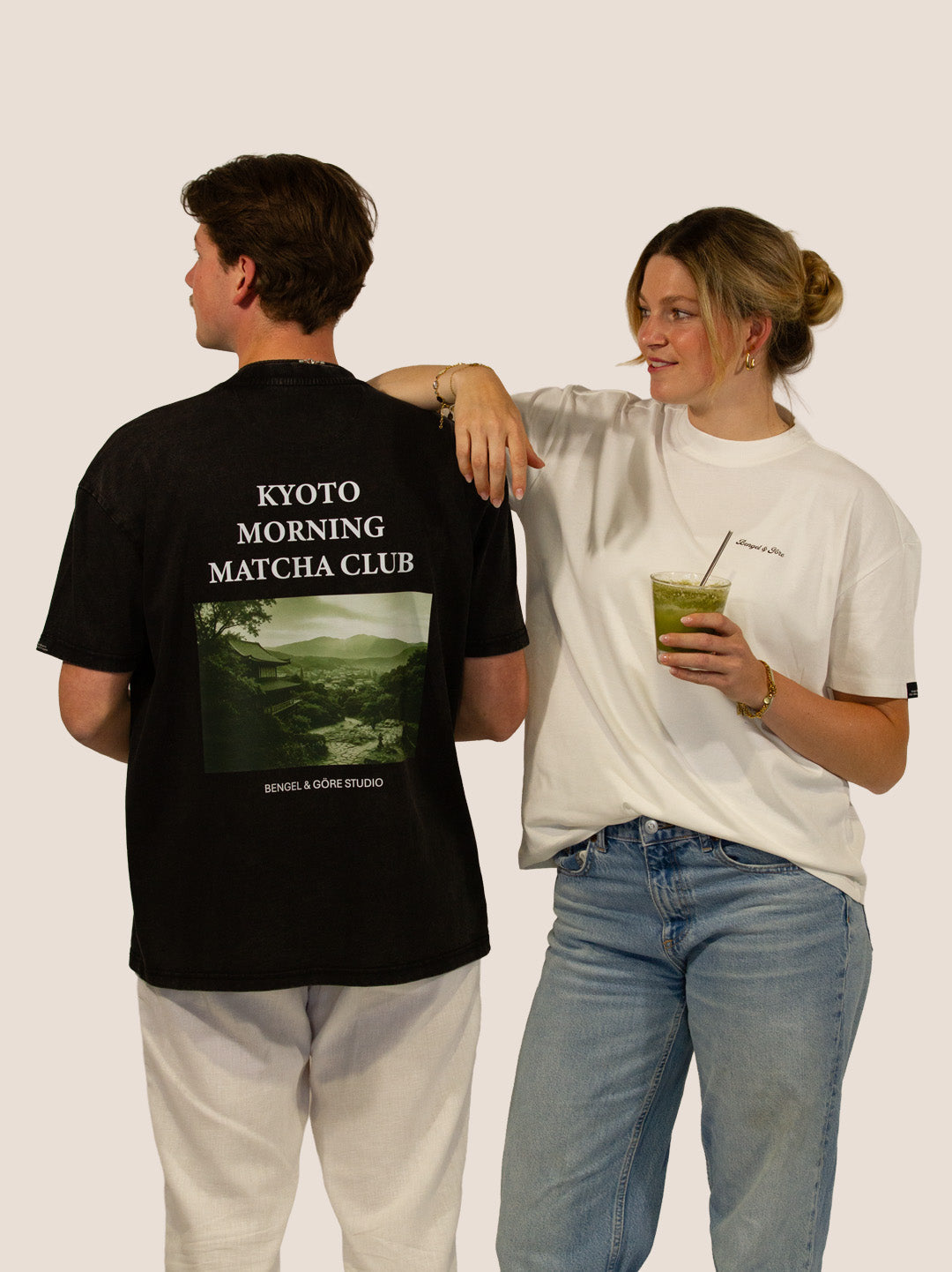 Mann im schwarzen „Kyoto Morning Matcha Club“ Heavy Tee, Frau in Off-White mit Matcha, Bengel & Göre.