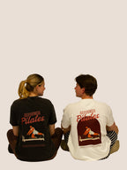 Frau und Mann sitzend in Bengel & Göre „Reformer Pilates“ Heavy Tees, Rückenprints in Schwarz und Off-White.