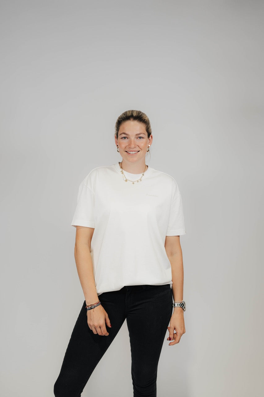 Frau im Off-White Bengel & Göre Heavy Tee mit Brust-Schriftzug und schwarzer Jeans, Vorderseite.
