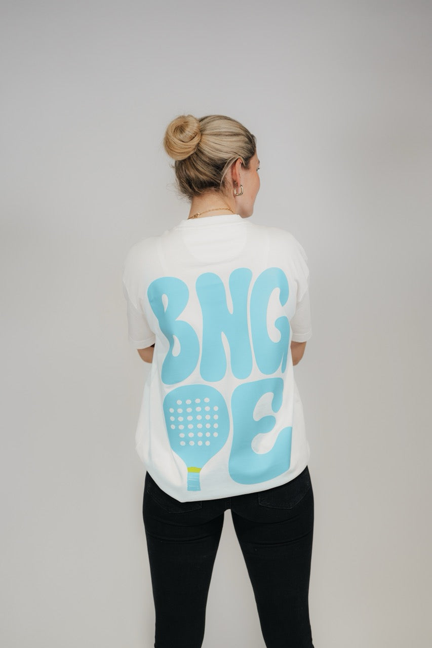 Frau im Off-White „BNGOE Padel“ Heavy Tee von Bengel & Göre, hellblauer Rückenprint.