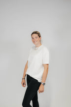 Lächelnde Frau im Off-White Bengel & Göre Heavy Tee, leicht seitliche Vorderansicht.
