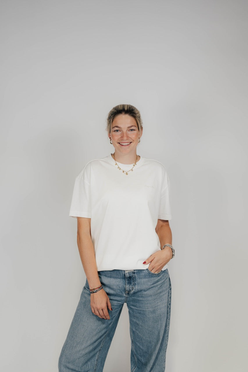Frau im Off-White Bengel & Göre Heavy Tee mit Brust-Schriftzug und Jeans, Vorderseite.