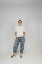 Frau im Off-White Bengel & Göre Heavy Tee mit Jeans und Sneakern, Ganzkörper-Vorderansicht.