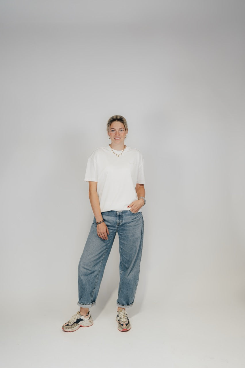 Frau im Off-White Bengel & Göre Heavy Tee mit Jeans und Sneakern, Ganzkörper-Vorderansicht.